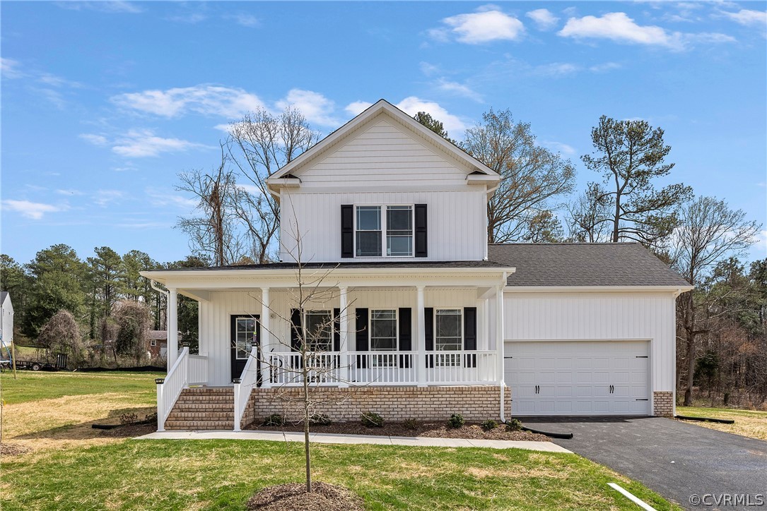 Completed white Craftsman-style home with covered front porch and two-car garage