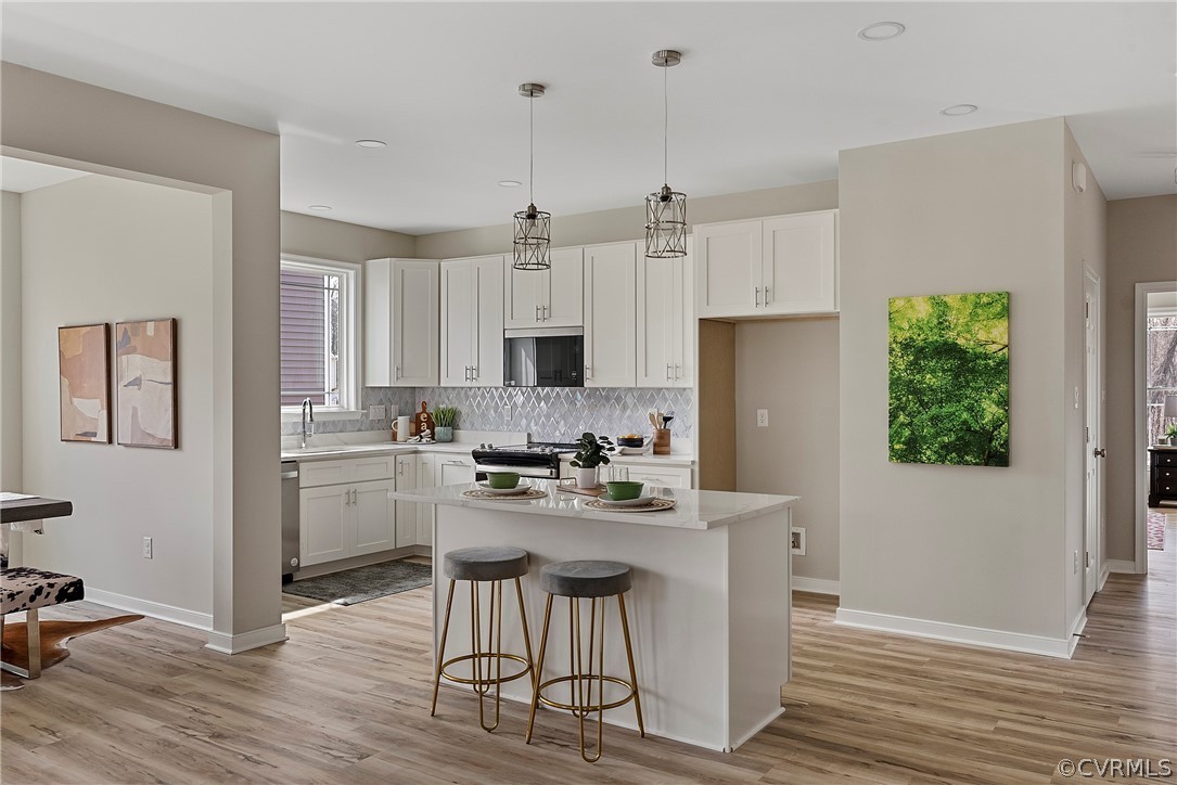Bright completed kitchen with an island, coordinated cabinets, appliances, and lighting