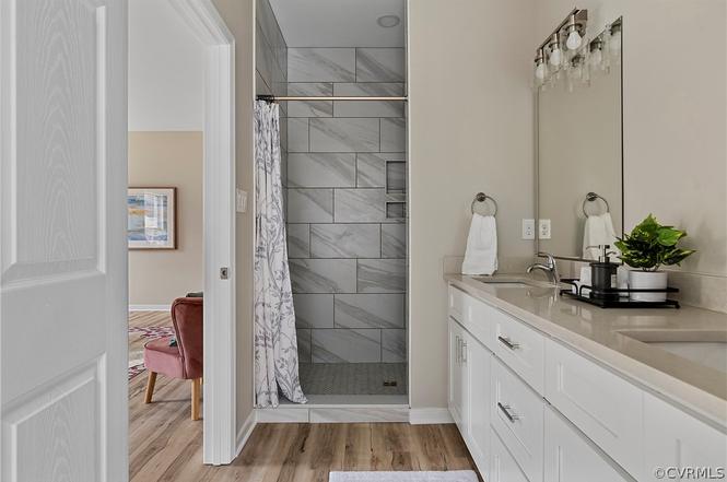 Primary bathroom with long white vanity and tiled walk-in shower